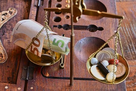 An old scale with money and tablets as a symbol of healthcare costs.の写真素材