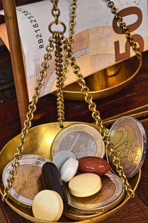 An old scale with money and tablets as a symbol of healthcare costs.の写真素材