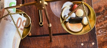 An old scale with money and tablets as a symbol of healthcare costs.の写真素材