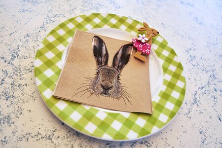 Colorful plate with a napkin showing an Easter bunny and a small felt Easter bunny on the edge.の写真素材