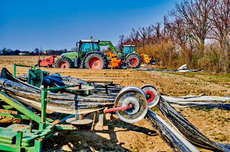 Brandenburg, Germany - March 28, 2020: View to tractors and machines that are ready to prepare an asparagus field in Germany for cultivation. The focus lies in the background.のeditorial素材
