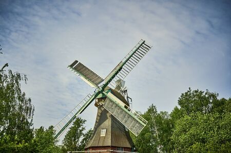 Historic and restored windmill in Berlin, Germany, between trees in spring.