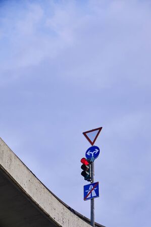 Bottom view of a red traffic light and various traffic signs at an intersection on a bridge in Berlin, Germany.の写真素材