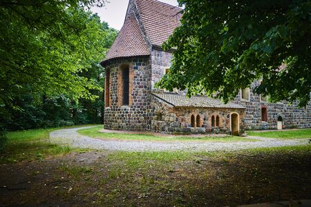 Details of a historic medieval church in Berlin, Germany. You can see parts of the building made of field stones, framed by trees.の写真素材