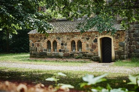Details of a historic medieval church in Berlin, Germany. You can see parts of the building made of field stones, framed by trees.の写真素材