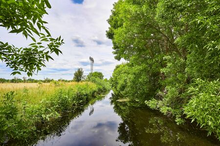 Cloudy sky over a little creek in the surrounding countryside of Berlin, Germany.の写真素材