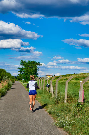 Berlin, Germany - July 21, 2020: A female jogger in sportswear from behind on the Berlin Wall path.のeditorial素材