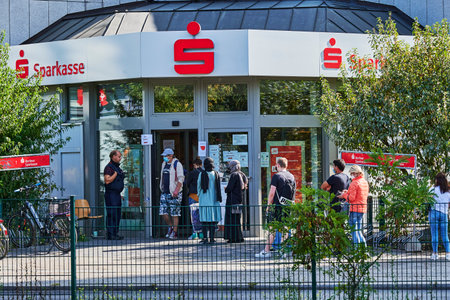 Berlin, Germany - September 17, 2020: Customers queuing in front of a bank branch, some of whom are...