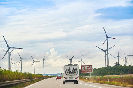 Freeway 20, Germany -September 2, 2020: Camper on the freeway 20 with a bike carrier attached to the stern and bicycles mounted on it. Near the freeway you can see wind turbines.のeditorial素材