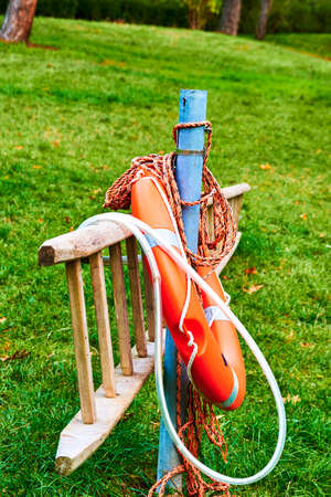 Ladder and orange lifebuoy at the edge of a lake in a park.の写真素材