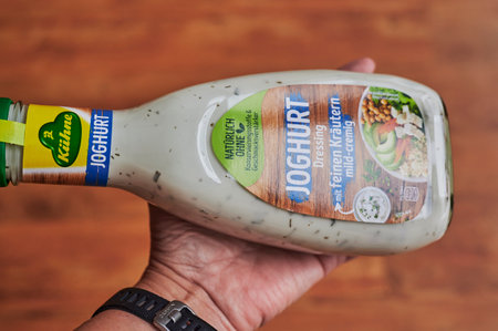 Berlin, Germany - November 20, 2020: Bottle with salad dressing and German lettering held in one hand.のeditorial素材
