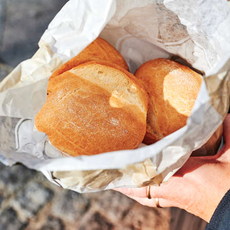 View into an open paper bag with fresh buns that is held in hands.の写真素材