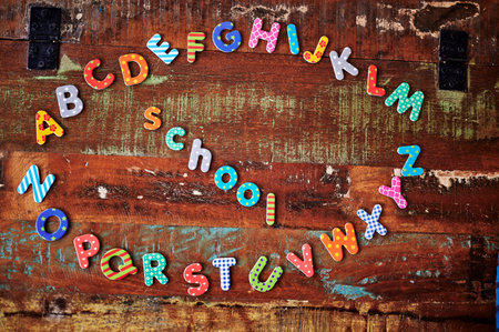 Auburn wooden table with colorful letters that show the alphabet lying in a circle.の写真素材