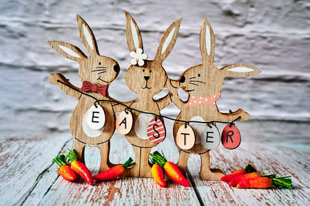 Three wooden Easter bunnies with decoration and the text Easter written on eggs.の写真素材
