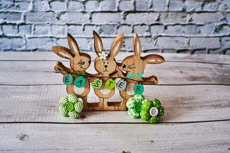 Three wooden Easter bunnies with decoration and the text Easter written on eggs.の写真素材