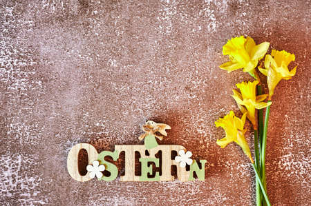 Wooden sign with an Easter bunny with flowers as decoration. The text is German for Easter.の写真素材