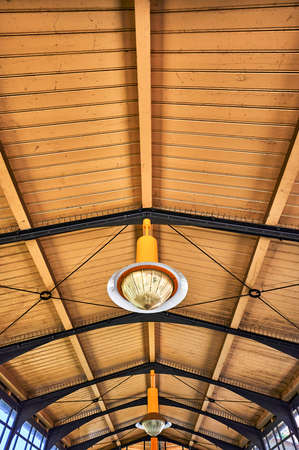 Details of a historic station building in Berlin, Germany. You see an old metal lamp under the wooden roof construction.の写真素材