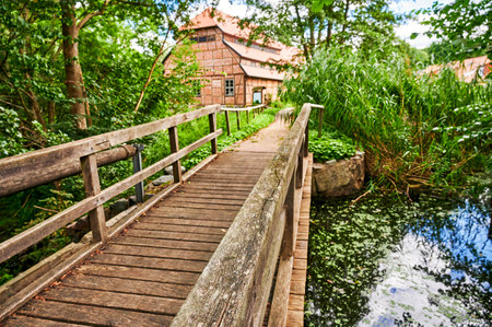 Wooden bridge over a creek as part of an old small weir near a historic watermill. The view above the bridge has the focus in the front area.のeditorial素材