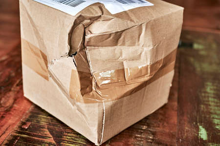 Cardboard package that was damaged in shipping and has a crack and dents.の写真素材
