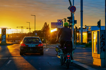 Berlin, Germany - June 23, 2021: Backlit photography of a road intersection with the glowing sun in the background and the shadowy vehicles in the foreground.のeditorial素材