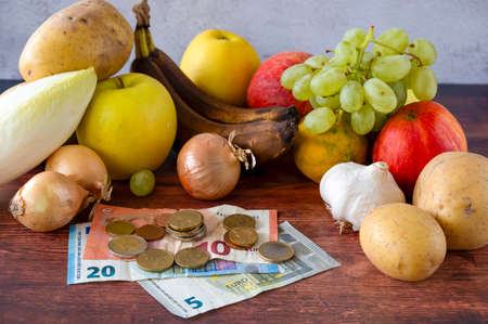Food lies on a wooden table along with European banknotes and coins symbolizing inflation.