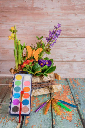 Pretty arrangement of various colorful spring flowers with decorations, a paint box and brushes.の写真素材