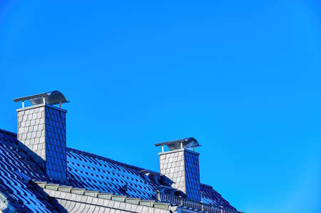 View of a roof with chimneys against a blue sky.の写真素材