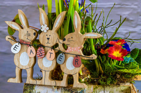 Flower arrangement with wooden Easter bunnies as decoration and the text Easter on the Easter eggs.の写真素材