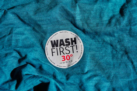 Sticker on a T-shirt with washing instructions and the text "Wash first".の写真素材