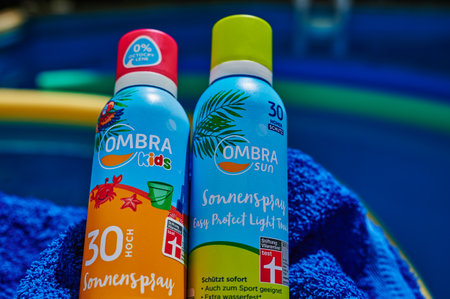 Berlin, Germany - July 24, 2022: Anti-sunburn spray on a blue towel by a swimming pool.