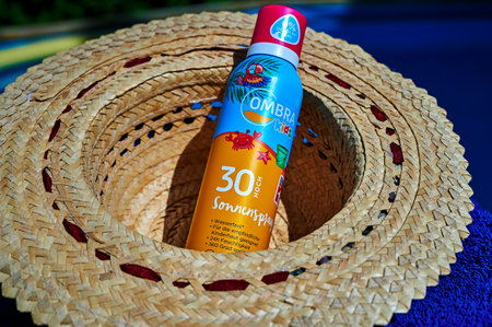 Berlin, Germany - July 24, 2022: Anti-sunburn spray on a blue towel by a swimming pool.のeditorial素材