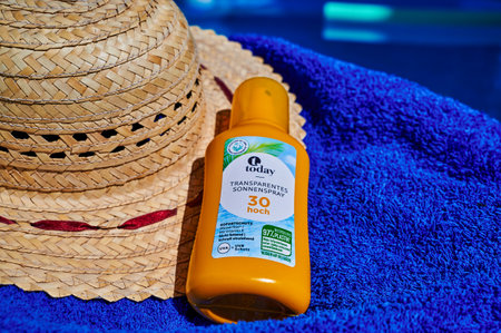 Berlin, Germany - July 24, 2022: Anti-sunburn spray on a blue towel by a swimming pool.のeditorial素材