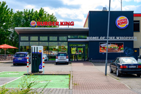 Berlin, Germany - August 6, 2021: Entrance area of a fast food restaurant and charging station for electric cars in its parking lot.のeditorial素材