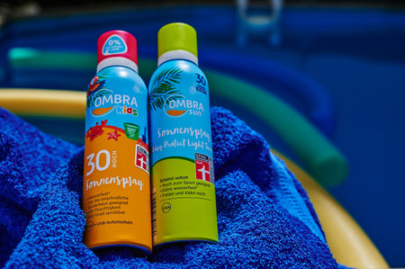 Berlin, Germany - July 24, 2022: Anti-sunburn spray on a blue towel by a swimming pool.のeditorial素材