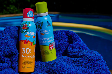 Berlin, Germany - July 24, 2022: Anti-sunburn spray on a blue towel by a swimming pool.のeditorial素材