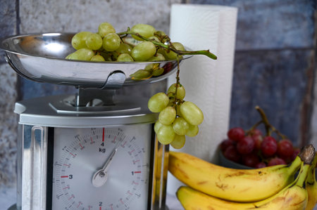 Various fruits on a kitchen countertop and on a kitchen scale.