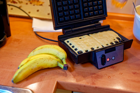 Waffle batter in a waffle iron with bananas as an ingredient.の写真素材