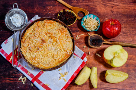 Freshly baked apple pie on a rustic kitchen worktop with ingredients and kitchen utensils.の写真素材