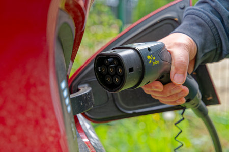 Berlin, Germany - April 24, 2024: Hand of a man plugging into the charger of an electric car.のeditorial素材