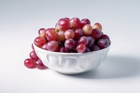 Bunch of red grapes in a white bowl on a white backgroundの素材