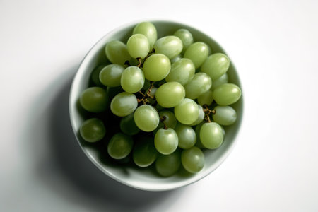 Green grapes in a bowl on a white background. Top view.の素材