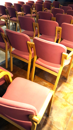 Multiple pink fabric and bent wood chairs in a meeting room