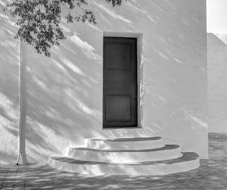 Whitewashed traditional church or hermita in a small village in Spain. Shadows cast over circular...