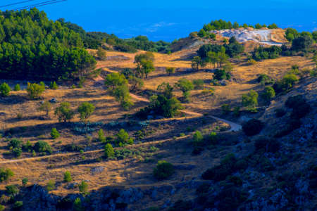 Grassy mountain with crolling clouds and blue sky. Misty valley in the background and craggy rocks and outcrops. Jamilenaの写真素材