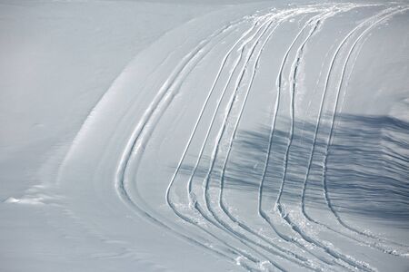 Ski tracks on a sunny winter slope. The shadow of the tree on the track. France, Savoie, Bessansの写真素材