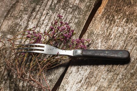 Antiquarian fork and dried flowers on an old wooden tableの写真素材