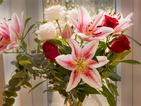 lilies with red and white roses in a bouquetの写真素材