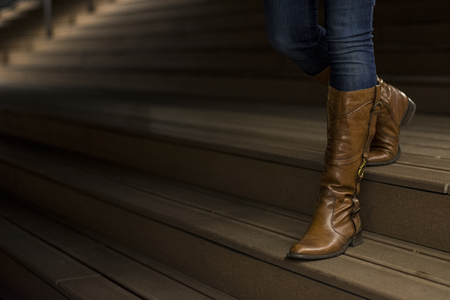 Closeup of woman's leather boots on wooden stairsの写真素材