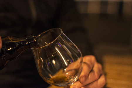 Bartender is pouring black beer in empty glassの写真素材