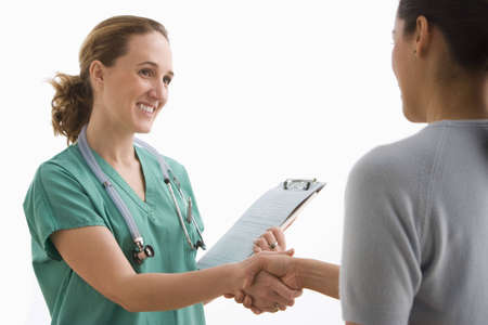 A young nurse is smiling and shaking hands with her patient. Horizontal shot. Isolated on white.の写真素材